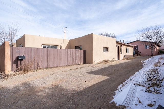 view of side of property with fence and stucco siding