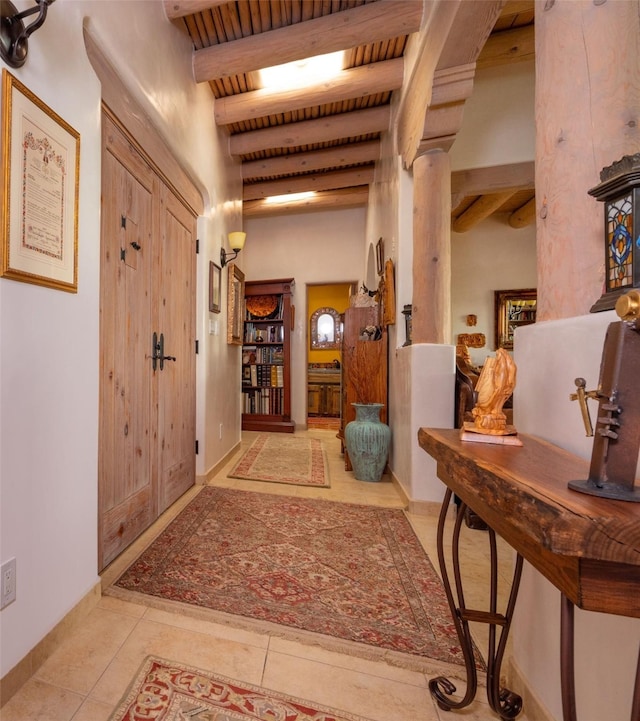 corridor featuring tile patterned flooring, baseboards, and beam ceiling