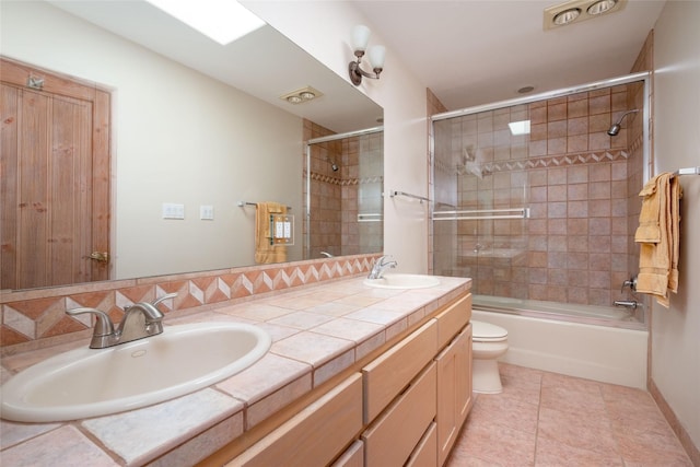 full bathroom with double vanity, a sink, toilet, and tile patterned floors