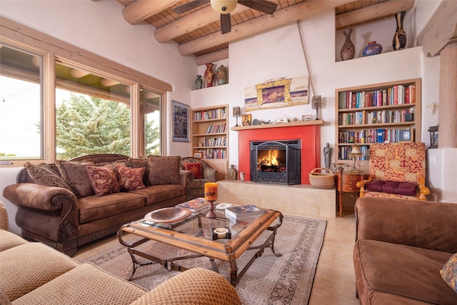 living room featuring a warm lit fireplace, wooden ceiling, ceiling fan, built in shelves, and beam ceiling