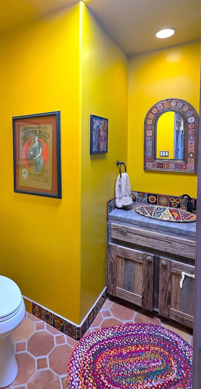 interior space featuring toilet, recessed lighting, vanity, baseboards, and tile patterned floors