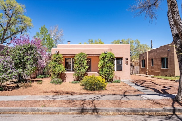 adobe home with stucco siding and fence