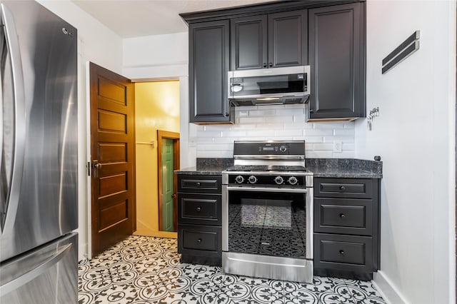 kitchen featuring appliances with stainless steel finishes, dark stone counters, light tile patterned flooring, and decorative backsplash