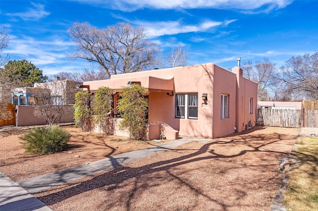 pueblo-style home with fence and stucco siding