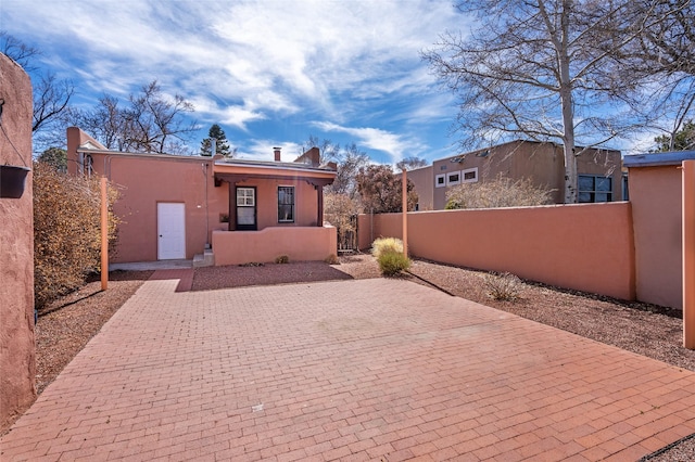 exterior space with a patio area, a fenced front yard, and stucco siding