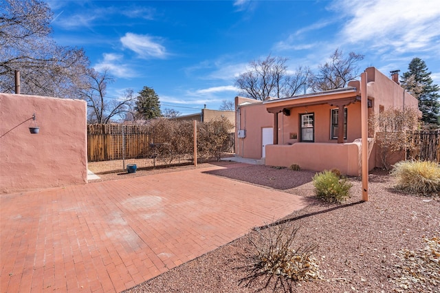 view of side of home with a fenced front yard, a patio, and stucco siding