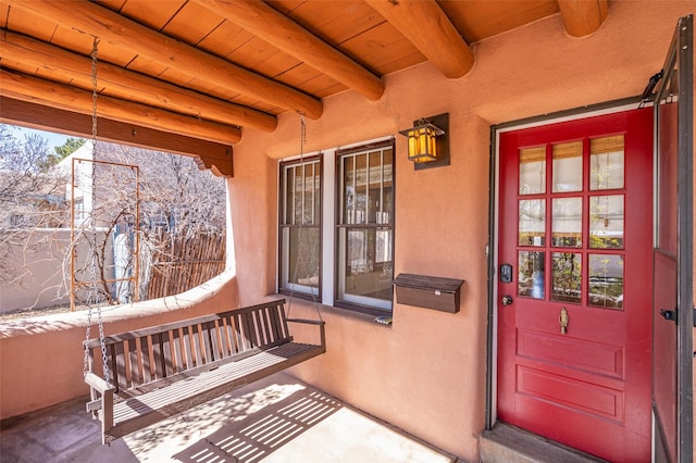 view of exterior entry with covered porch and stucco siding