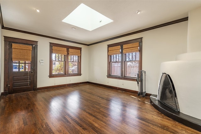 unfurnished living room featuring crown molding, a skylight, plenty of natural light, and wood finished floors