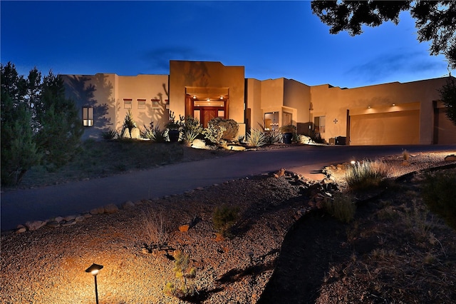 pueblo revival-style home featuring a garage and stucco siding