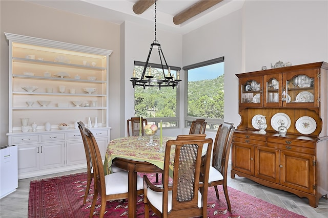 dining area featuring beamed ceiling and an inviting chandelier