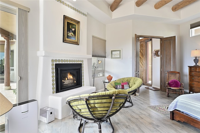 sitting room featuring beam ceiling, wood finished floors, a fireplace, and ornate columns