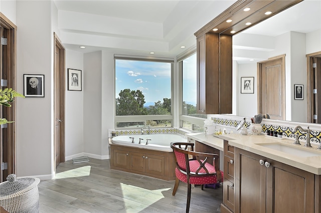 full bath featuring a garden tub, wood finished floors, recessed lighting, baseboards, and vanity