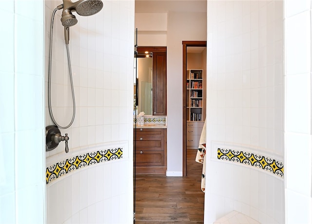 full bath featuring tiled shower, vanity, and wood finished floors