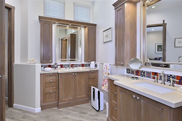 bathroom featuring decorative backsplash, wood finished floors, two vanities, and a sink