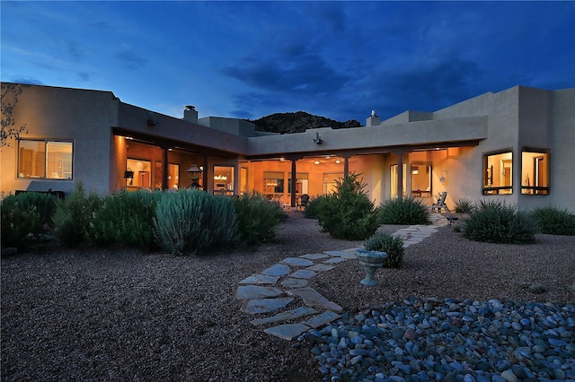 rear view of property featuring stucco siding, a chimney, and a patio