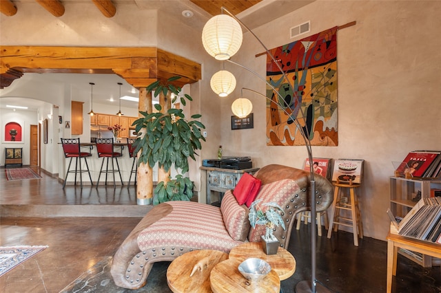 living room featuring arched walkways, visible vents, finished concrete flooring, and a towering ceiling