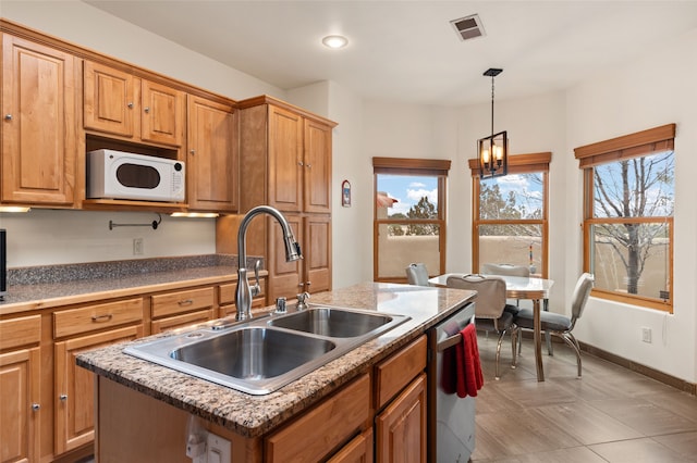 kitchen with white microwave, visible vents, an island with sink, a sink, and dishwasher