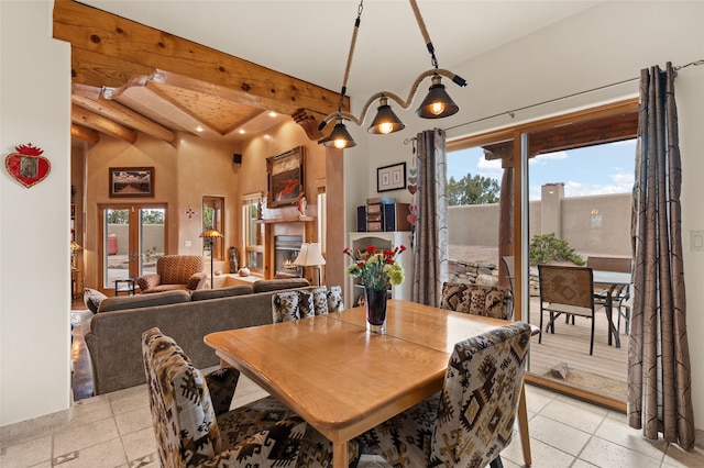 dining space with light tile patterned floors, french doors, a healthy amount of sunlight, and a glass covered fireplace