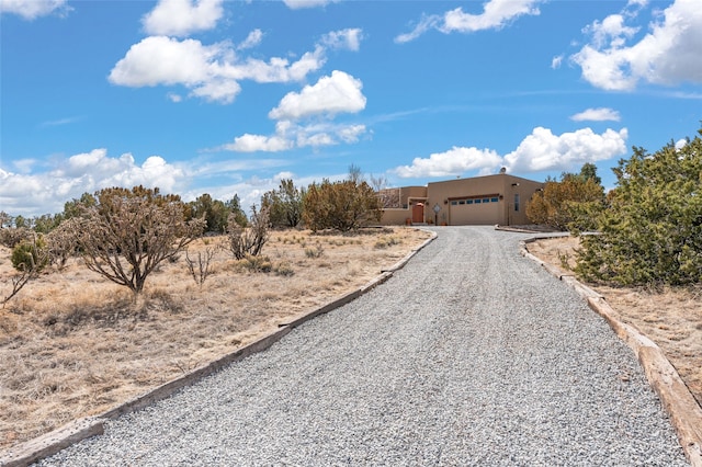 view of front of property with stucco siding, an attached garage, and gravel driveway