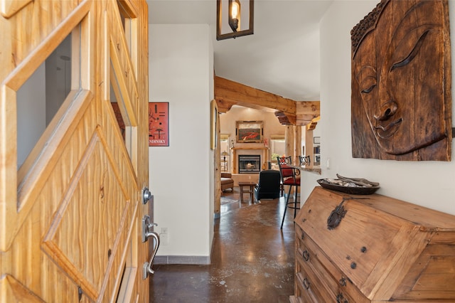 entrance foyer featuring baseboards, a lit fireplace, and finished concrete flooring