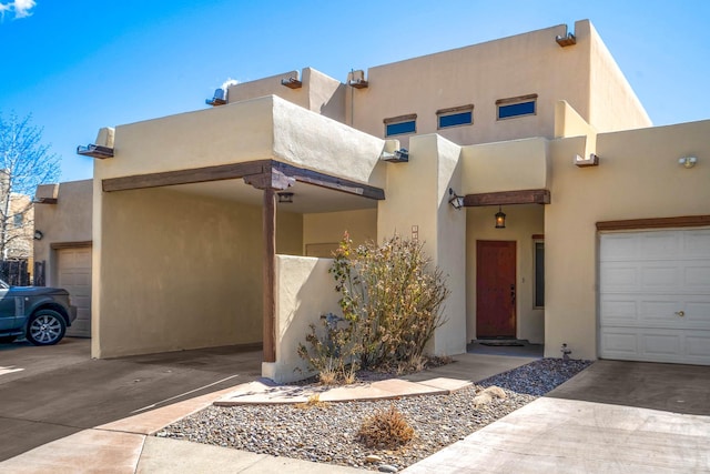 adobe home with a garage, driveway, and stucco siding