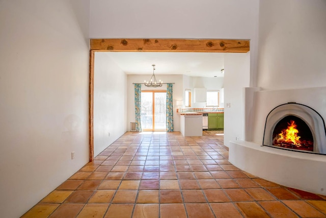 unfurnished living room featuring light tile patterned floors, a notable chandelier, and a lit fireplace