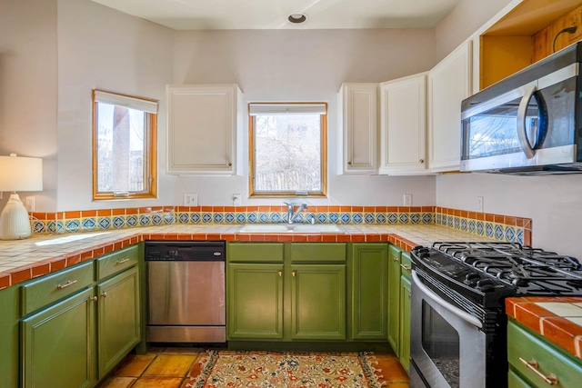 kitchen featuring a wealth of natural light, a sink, white cabinetry, stainless steel appliances, and green cabinets