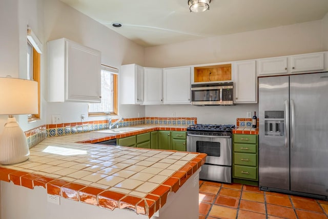 kitchen with green cabinetry, stainless steel appliances, and white cabinetry
