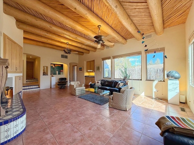 living area featuring visible vents, beamed ceiling, light tile patterned floors, wooden ceiling, and arched walkways