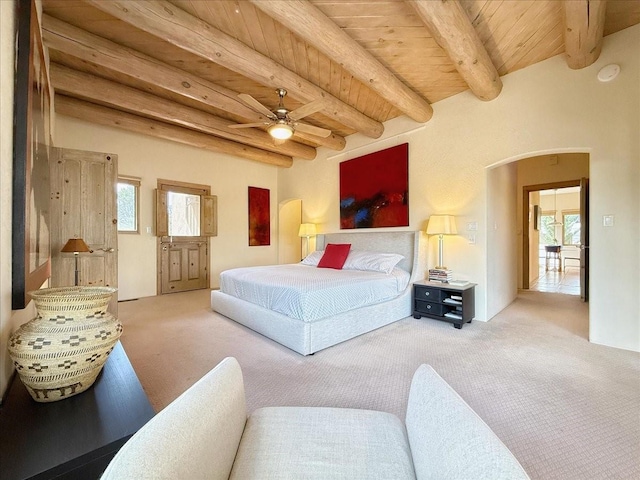 carpeted bedroom with beamed ceiling, multiple windows, wood ceiling, and arched walkways