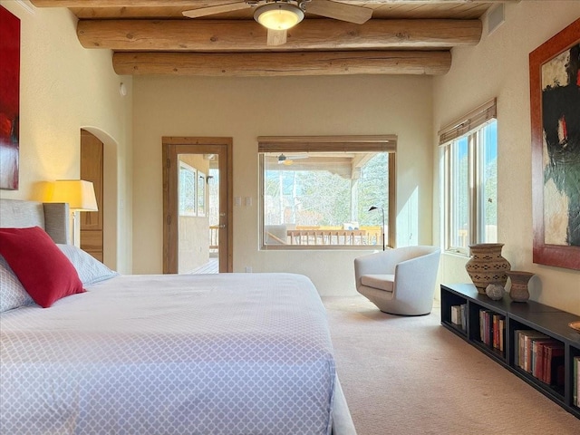 carpeted bedroom featuring arched walkways, beamed ceiling, multiple windows, and a ceiling fan