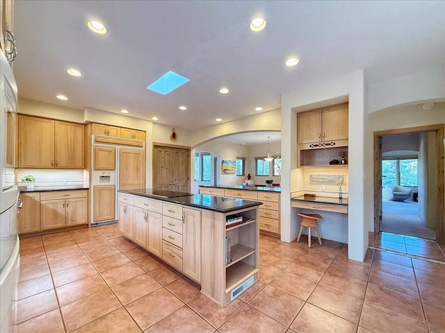 kitchen with open shelves, dark countertops, paneled built in refrigerator, and a wealth of natural light