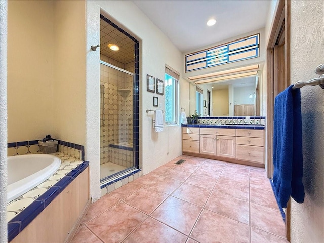 full bathroom featuring vanity, a bath, a shower stall, and tile patterned flooring