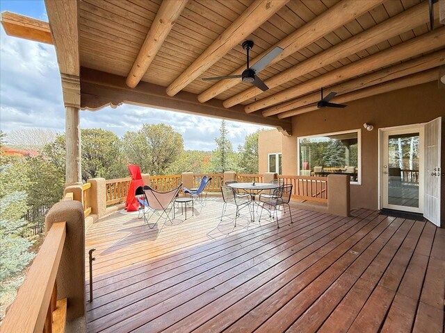 wooden terrace with outdoor dining area and ceiling fan