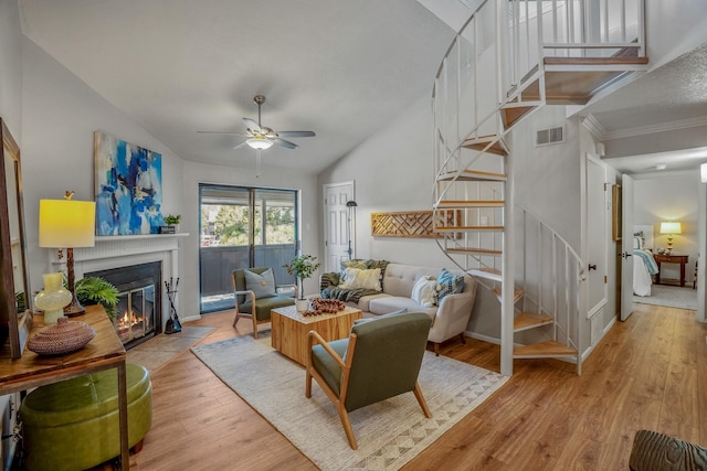 living area featuring visible vents, stairway, a fireplace with flush hearth, vaulted ceiling, and light wood-style flooring