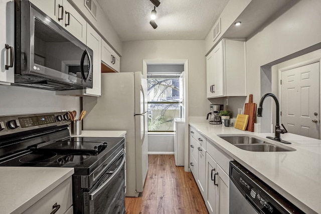 kitchen with a textured ceiling, light countertops, appliances with stainless steel finishes, and a sink