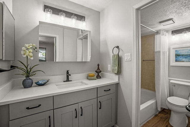 full bathroom featuring shower / bath combo with shower curtain, toilet, vanity, wood finished floors, and a textured ceiling