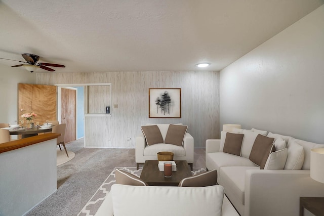 living room featuring carpet floors, a textured ceiling, and ceiling fan