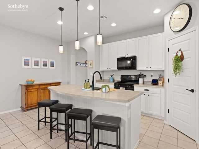 kitchen with visible vents, black appliances, a sink, a kitchen breakfast bar, and light countertops