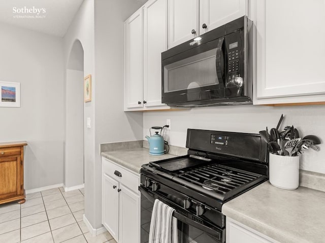 kitchen featuring light tile patterned floors, arched walkways, black appliances, white cabinets, and light countertops