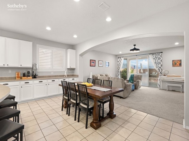 dining area featuring arched walkways, light tile patterned floors, recessed lighting, and light carpet