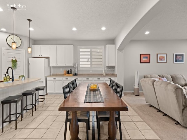 dining room featuring a textured ceiling, recessed lighting, arched walkways, light tile patterned floors, and baseboards