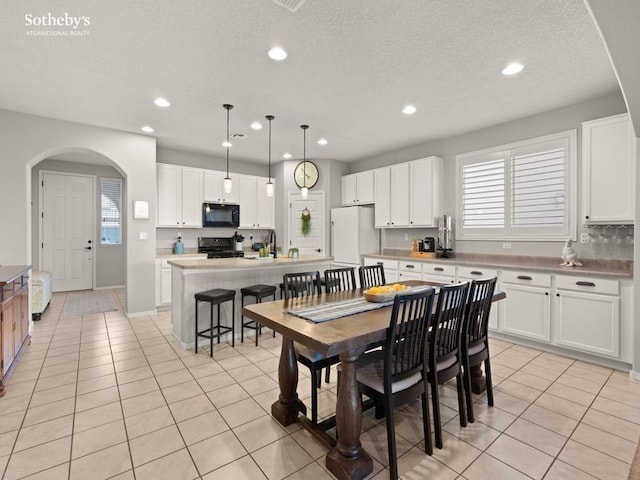 dining space with light tile patterned floors, recessed lighting, arched walkways, and a textured ceiling