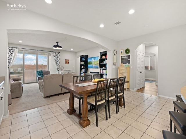 dining area with baseboards, light colored carpet, light tile patterned floors, recessed lighting, and arched walkways