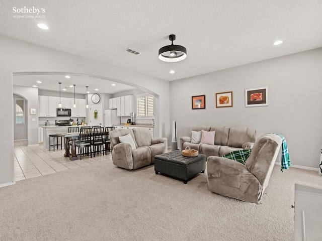 living area featuring visible vents, light carpet, recessed lighting, arched walkways, and light tile patterned flooring