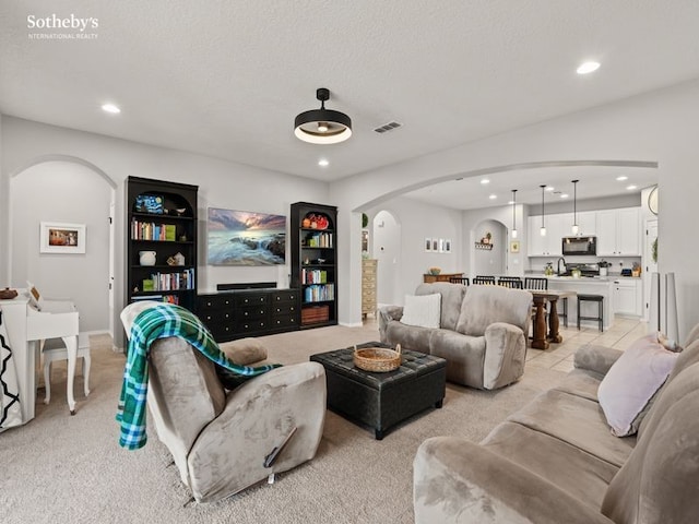 living room with visible vents, light tile patterned flooring, recessed lighting, arched walkways, and a textured ceiling