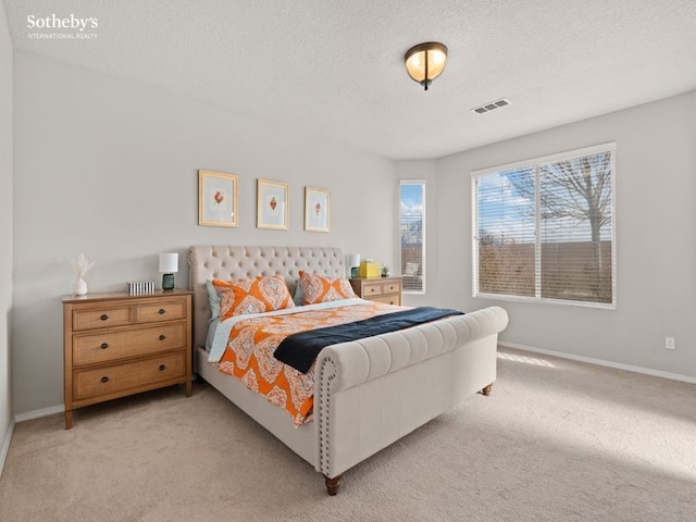 bedroom featuring visible vents, light colored carpet, a textured ceiling, and baseboards