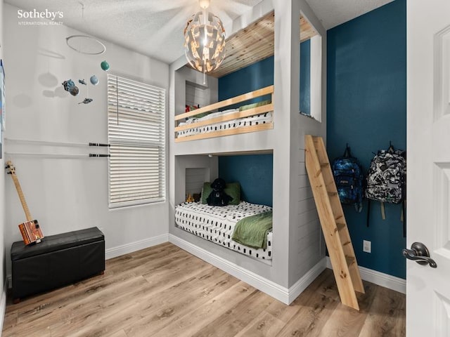 bedroom with an inviting chandelier, wood finished floors, and baseboards