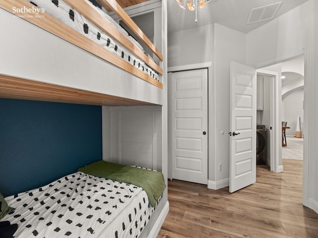 bedroom featuring visible vents, arched walkways, a closet, and wood finished floors