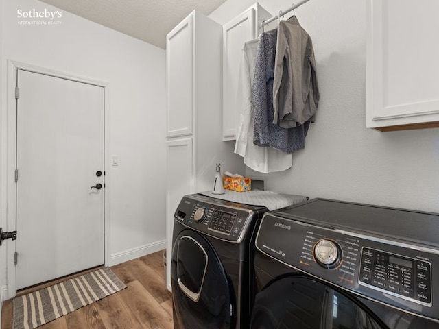 laundry area with baseboards, cabinet space, wood finished floors, and washing machine and clothes dryer